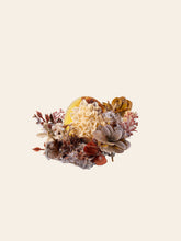 The Magnolia Birth Flower Ring by CAMELLIA features a carved flower centerpiece amidst dried flowers and foliage against a light background, akin to finely handcrafted jewelry where each detail mirrors the meticulous curation found in custom floral rings.
